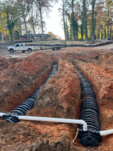 Excavated trench with drainage pipes and truck
