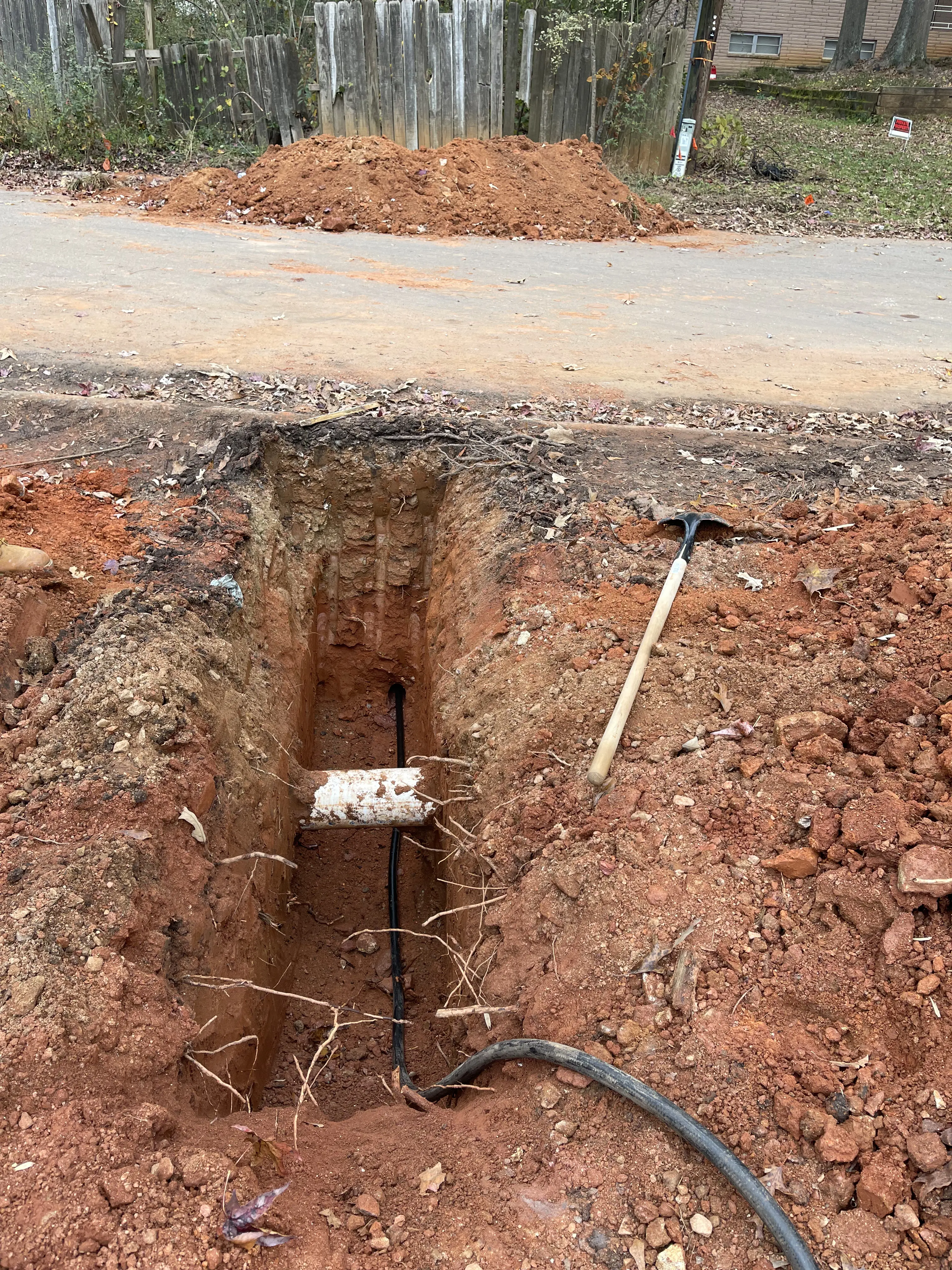 Trench with exposed utility pipe in orange soil